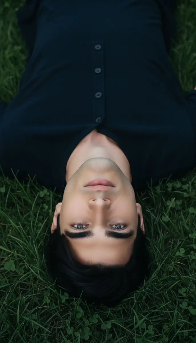 Intense Gaze: Man Lying Upside Down on Green Grass
