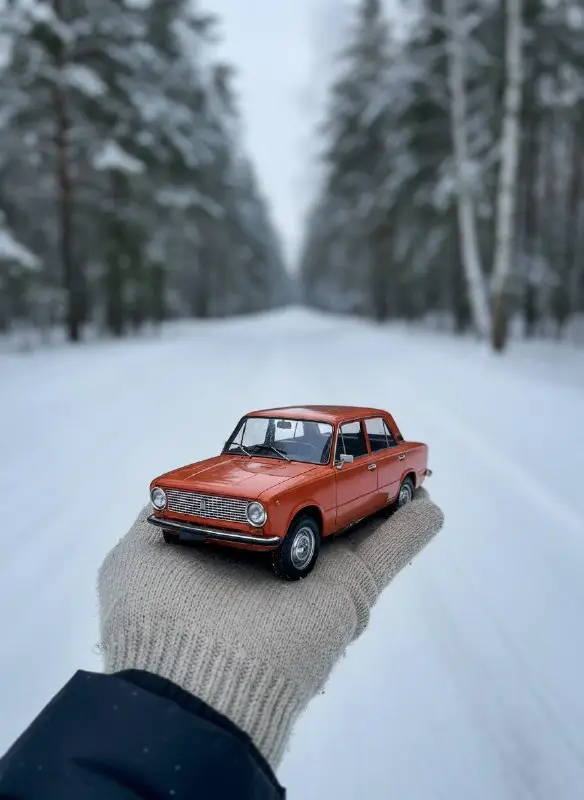 Miniature Orange Vintage Car Held in Snowy Winter Forest