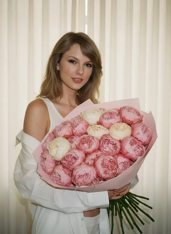 Beautiful woman with blonde hair holding pink peonies bouquet