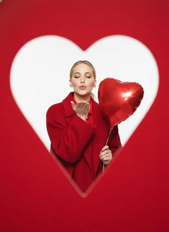 Woman blowing a kiss with heart balloon in heart frame