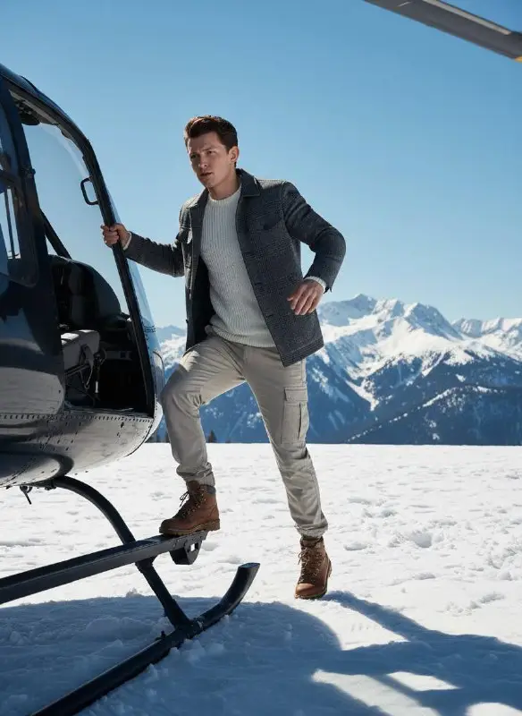 Stylish man boarding helicopter in snowy mountain landscape
