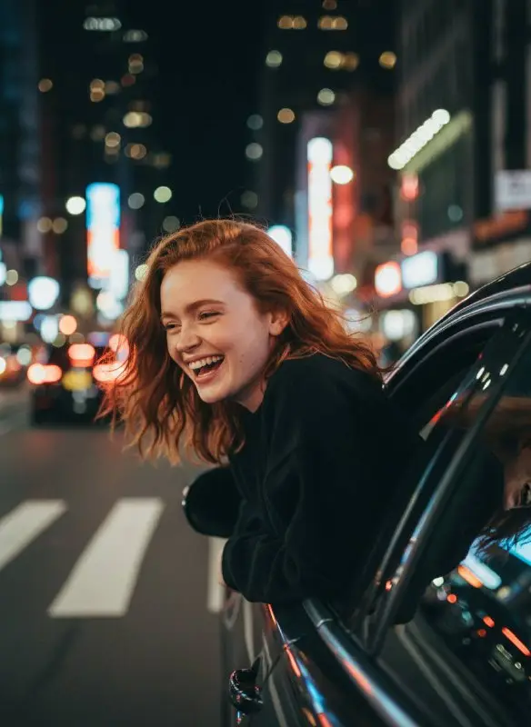 Young Redhead Woman Laughing Out of Car Window at Night