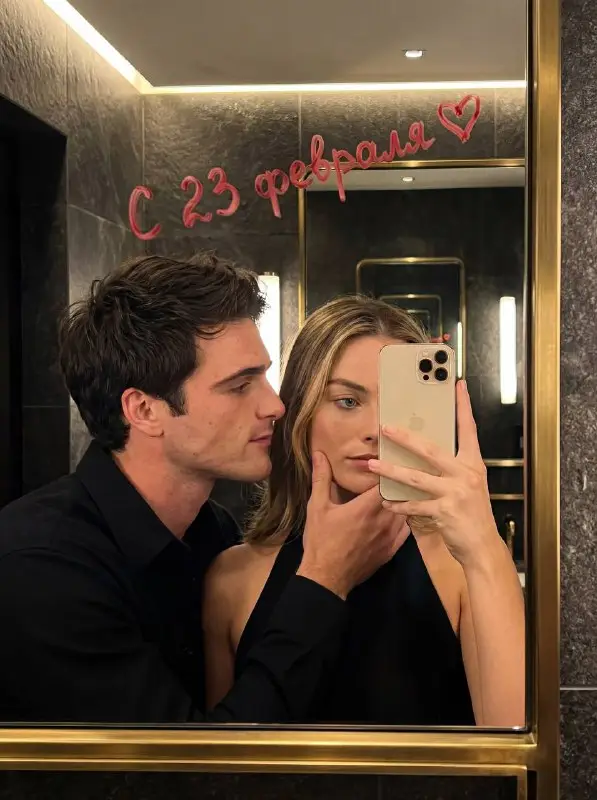 Romantic couple taking mirror selfie with lipstick message on mirror