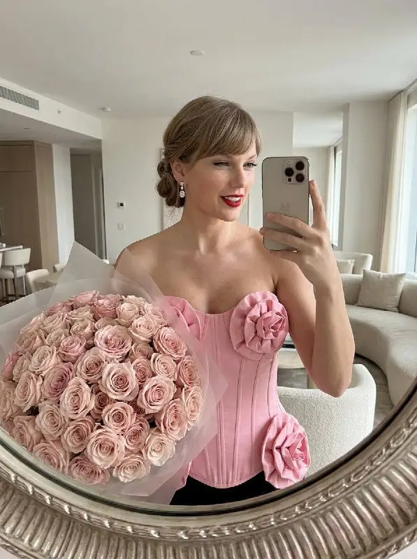 Woman in pink floral corset taking mirror selfie with rose bouquet