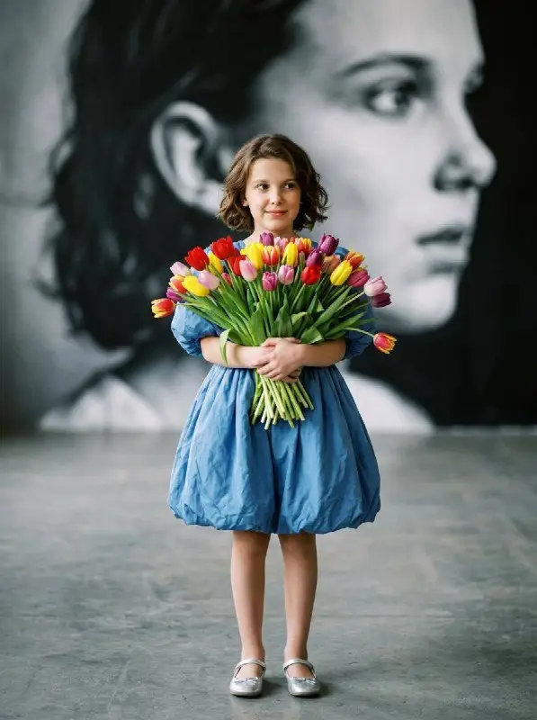Young girl in blue dress holding colorful tulip bouquet