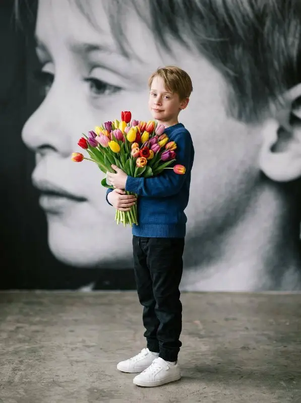 Young Boy Holding Large Bouquet of Colorful Tulips Portrait