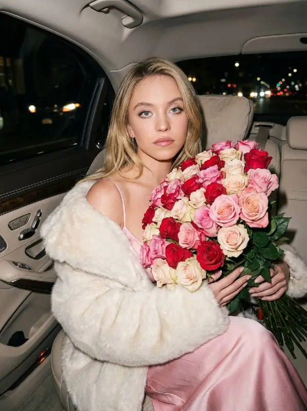 Elegant woman in fur coat holding large rose bouquet in car