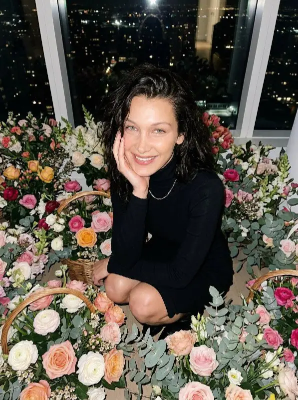 Beautiful woman in black dress surrounded by colorful flower baskets