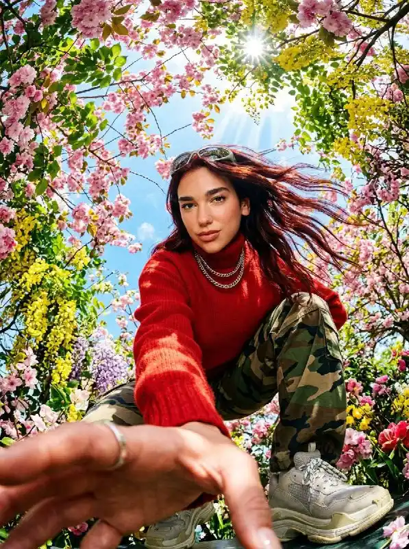 Fashionable woman in red sweater and camo pants under cherry blossoms