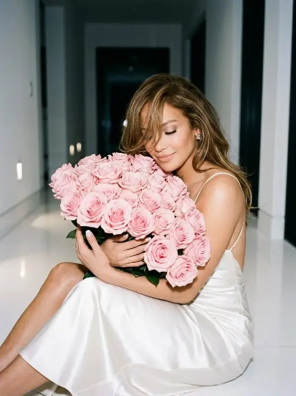 Elegant Woman in White Silk Dress Hugging Pink Roses Bouquet