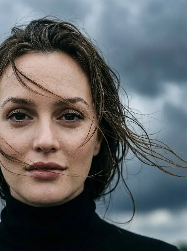 Moody outdoor portrait of a woman with windblown hair under stormy sky